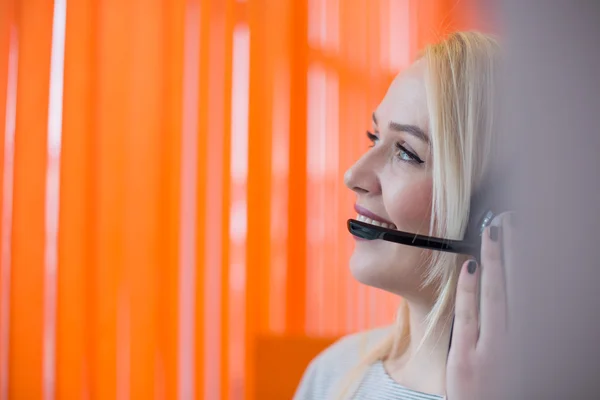 Smiling young business woman wearing a headset answering calls a