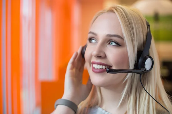 Portrait of support phone operator in headset at workplace. To p