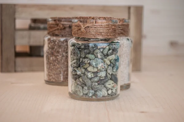 Small glass jars with sand and stones from the beach