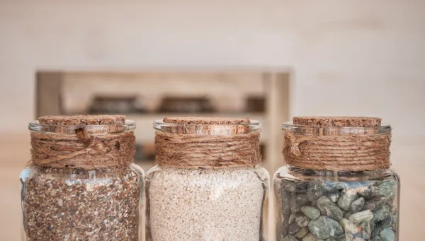 Small glass jars with sand and stones from the beach
