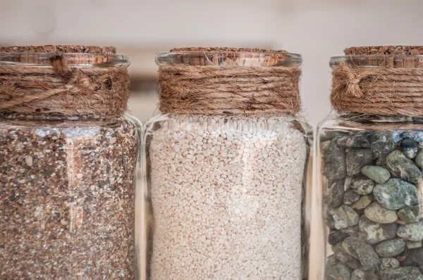 Small glass jars with sand and stones from the beach