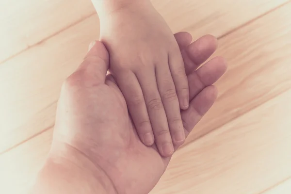 Hands clasped together on wood background