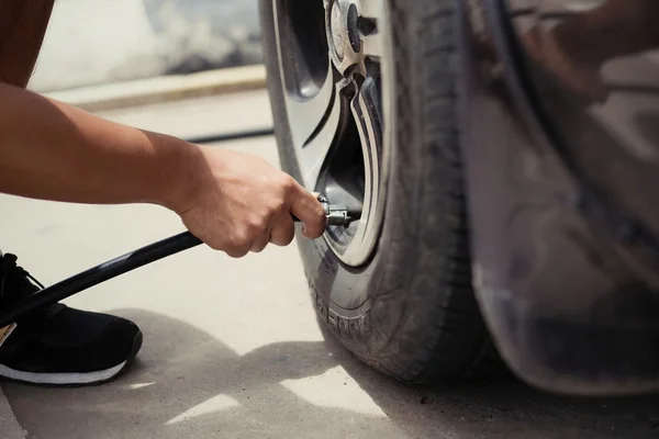 Man driver checking air pressure and filling air in the tires of