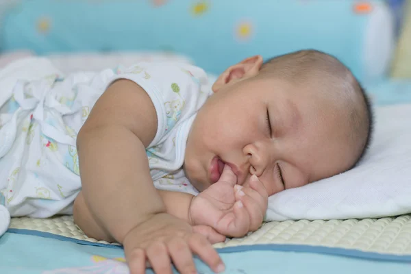 Asian baby sleeping white bed linen.
