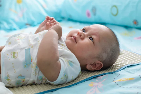 Asian baby sleeping is suck white bed linen.