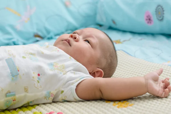 Asian baby sleeping is suck white bed linen.