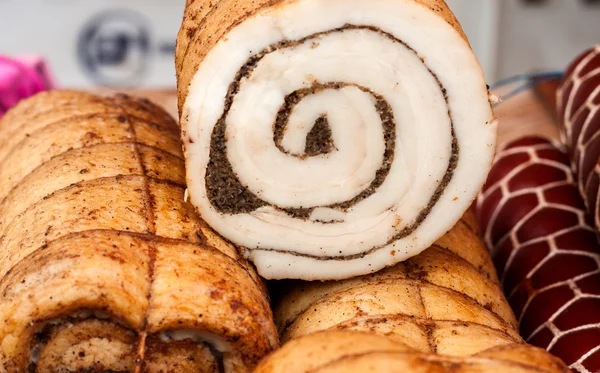 Photo closeup traditional ukrainian preserved salted spicy pepper rolled lard bacon pork fat with garlic and allspice berries on wooden cutting board on timber background, horizontal picture