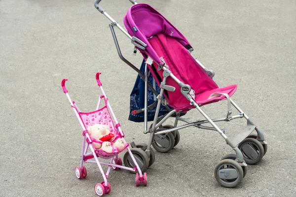 Two strollers for baby and doll in the street