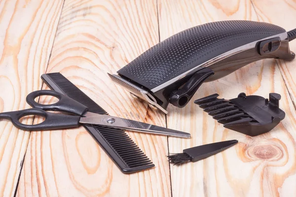 Hair trimmer with comb and scissors on the wooden background
