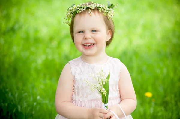 Sweet baby girl in wreath of flowers smiling outdoors