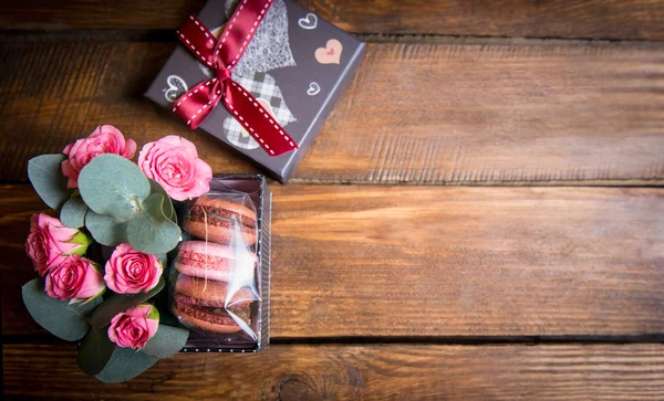 Bouquet of roses and cookies in gift box on a wooden table