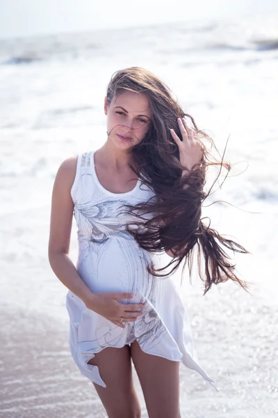 Beautiful tender pregnant woman stand on the sea shore