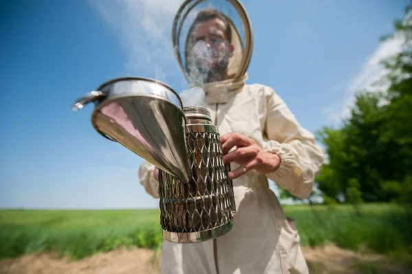 Beekeeper with smoke tool. making clouds