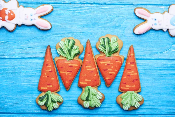 Colorful easter rabbit and carrot cookies on blue wooden background