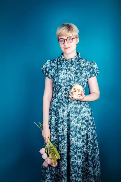 Girl holding flowers and skull on a blue background
