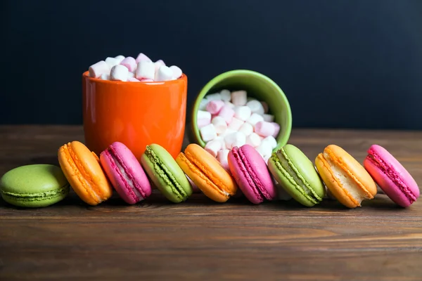 French macaroons and marshmellow in dark wooden background