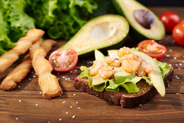 Rye bread sandwich with shrimp, avocado, tomatoes and breadsticks