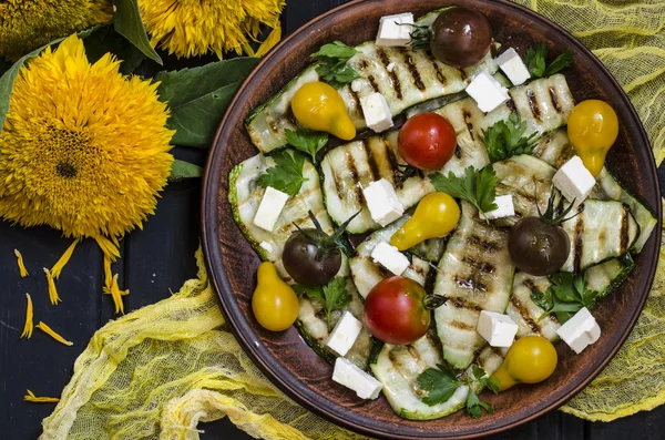 Grilled zucchini salad with cherry tomatoes and feta with sunflowers