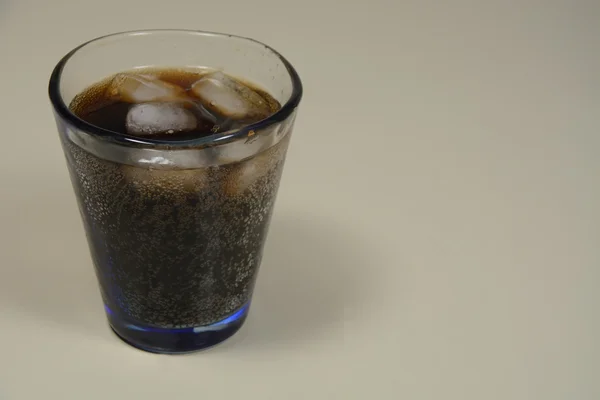 Cola soda pop and ice cubes in handcrafted glass on kitchen counter