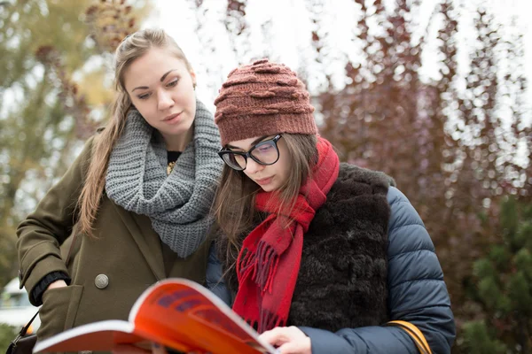 Two female students reading book