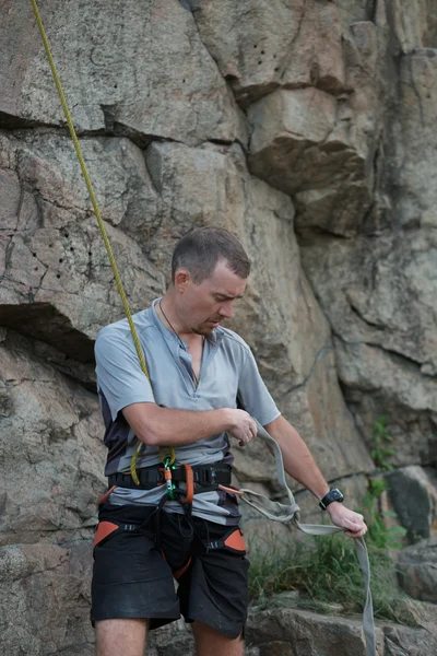 Male rock climber prepare equipment before climb to a cliff