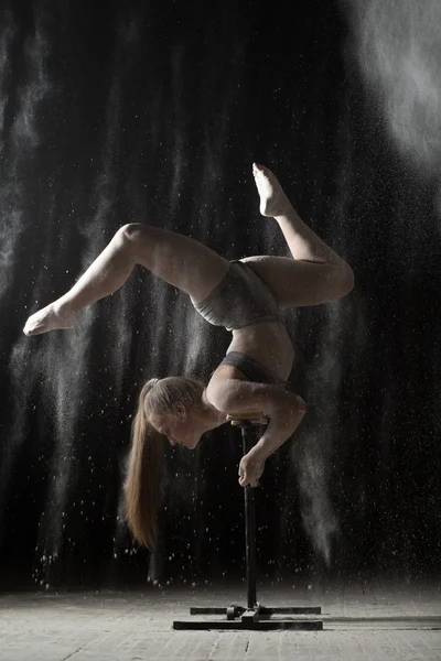 Gymnastic woman handstand on equilibr at sprinkled flour