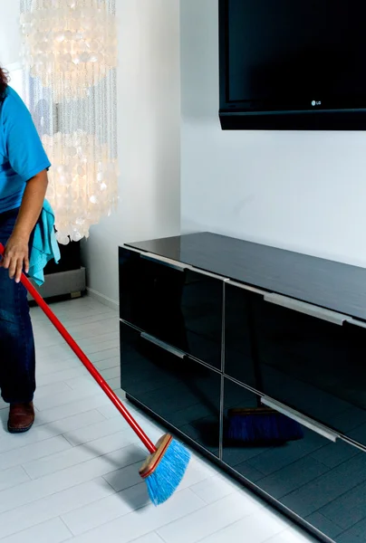 Maid sweeping the bedroom floor with broom