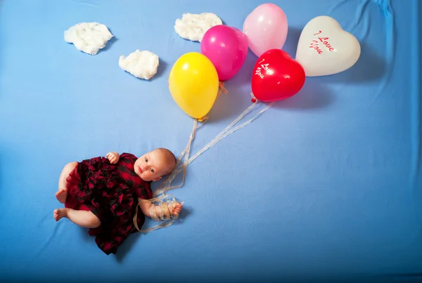 Baby flies on balloons in the clouds lying on the bed