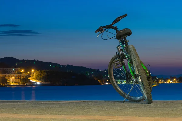 Mountain bicycle against the sea and the beautiful sunset at Kalamos village in Greece. Focus on the bike and the night view of Kalamos.