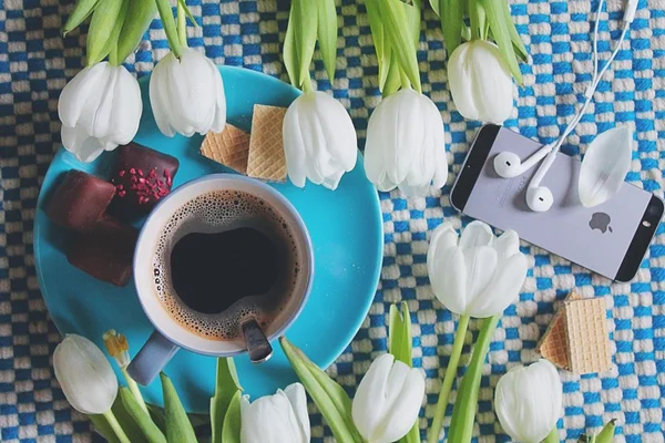 Coffee, sweets, tulips and smartphone with earphones
