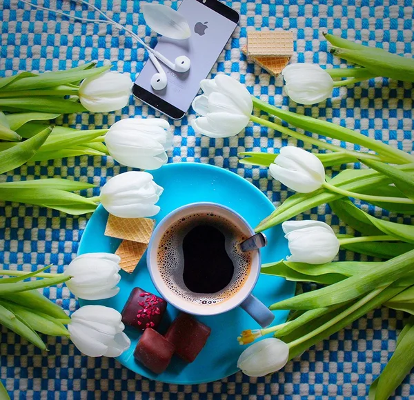 Cup of coffee, sweets, smartphone and tulips