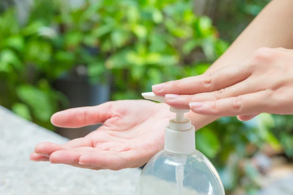 Female hands using wash hand sanitizer gel pump dispenser.