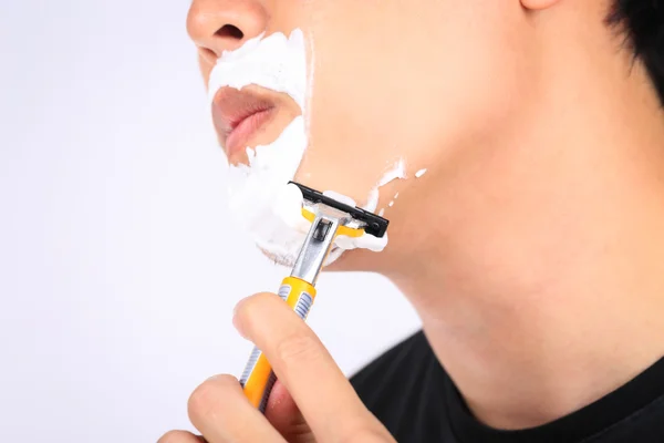 Close up young man shaving his face.
