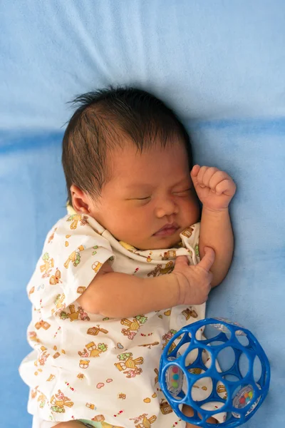 Newborn baby sleeping on blue fur fabric bed.