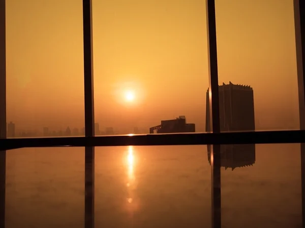 Sunrise morning. Silhouettes of glass window with orange sunrise background. View from high office building.