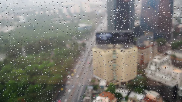 Water drop on the mirror wall after rainy. See the building outside the wall.