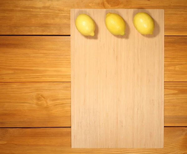 Banner for design menu of cafe  or recipe cooking: three lemon lie on a bamboo panel on rustic vintage table from brown textured boards.