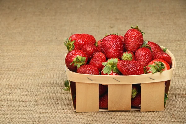 Strawberry in wooden basket on jute canvas