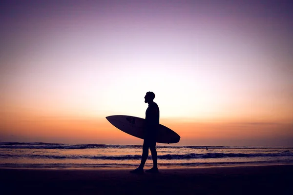 Silhouette of surfer man at sunset
