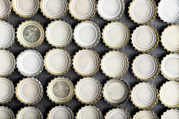 Caps of beer lined up in rows top view