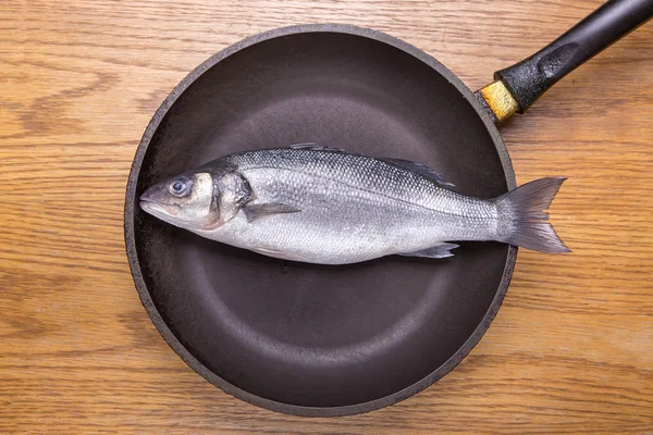 Sea bass fish in a frying pan, healthy food. top view