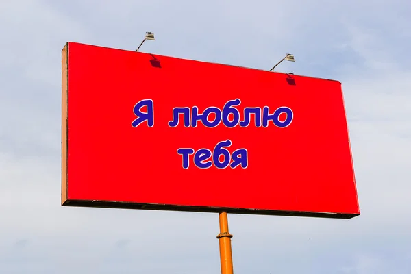 I love you: an inscription in Russian on red billboard on the sky background