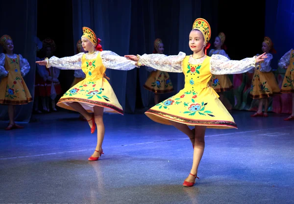 Two little girls dancing folk dance in yellow Russian folk costu
