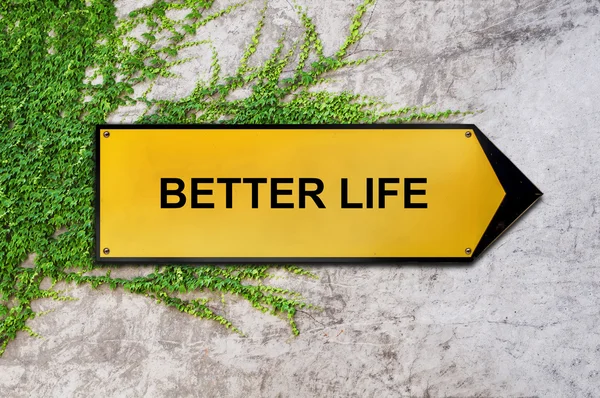 Better life on yellow sign hanging on ivy wall