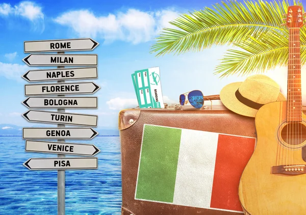Concept of summer traveling with old suitcase and Italy town sign with burning sun