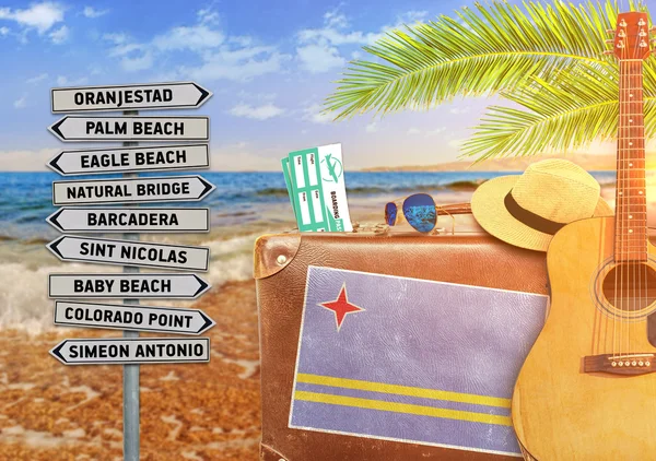 Concept of summer traveling with old suitcase and Aruba town sign with burning sun