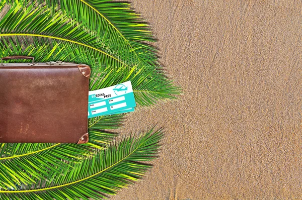 Palm trees, suitcase and ticket on sandy beach