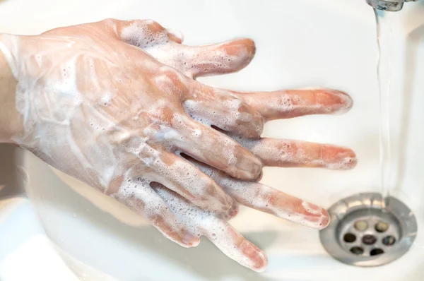 Washing of hands with soap under running water, close up
