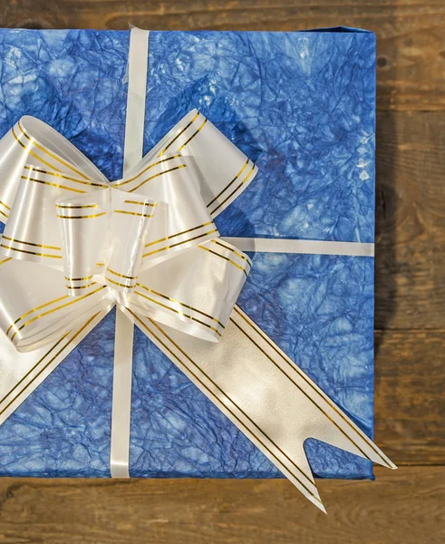 Blue gift box with white and golden ribbon and bow