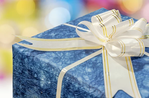 Blue gift box with white and golden ribbon and bow